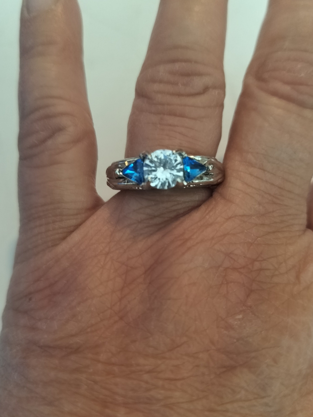 Silver Tone Ring with Blue Accent Stones and Clear Center Stone